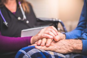 End-of-life care patient holding hands with caregiver at Tore's Home in Brevard, NC